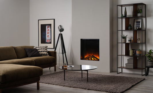 Electric fireplace by British Fires featuring a New Forest 650 SQ slate effect with a realistic flame display in a cozy room setting.