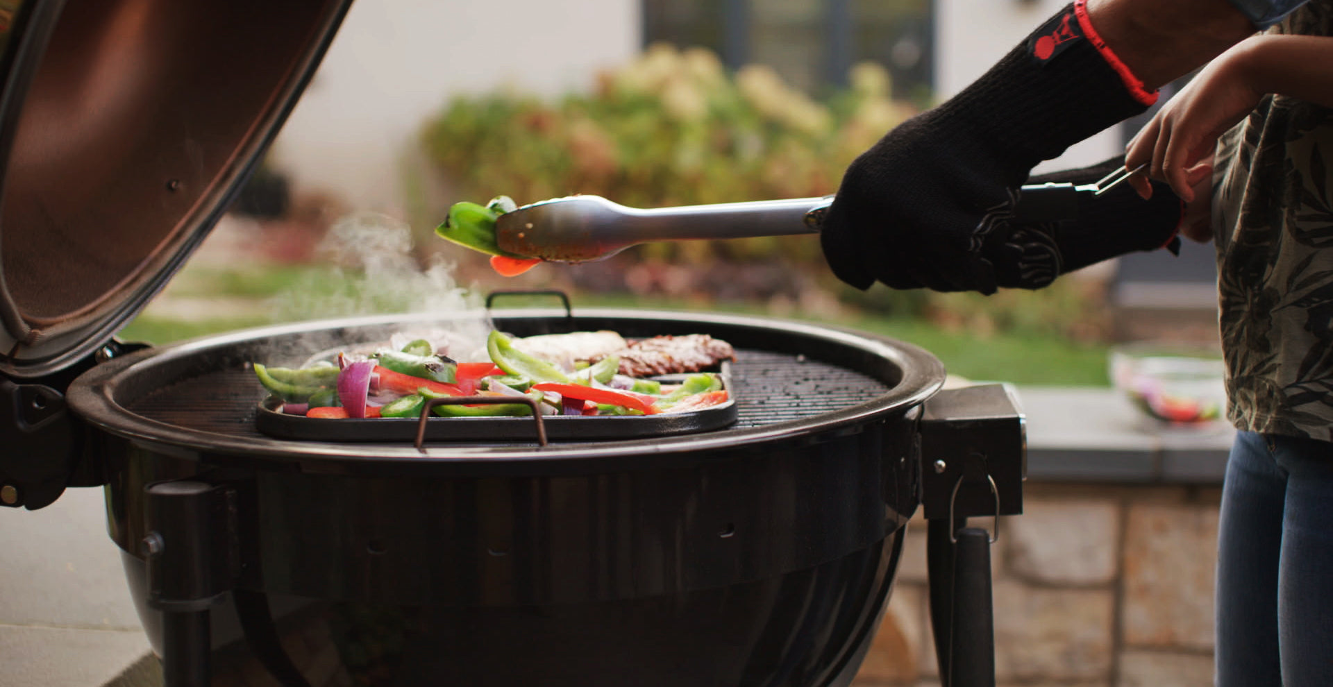 Person grilling vegetables on a barbecue grill outdoors