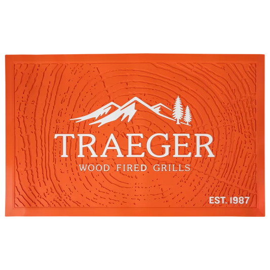 Traeger grill mat for BBQ accessories, showing a black, non-slip grill mat in front of a Traeger grill for protection and grilling convenience.